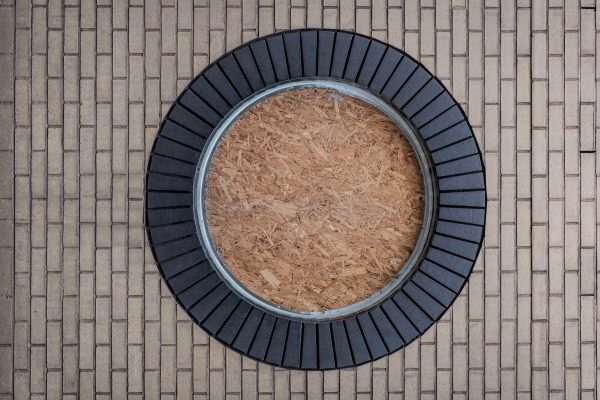 View of a round paved space. Tan bricks and black stone.